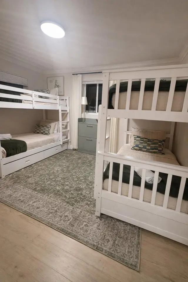 Bunk room at Even Keel with white bunk beds and green bedding