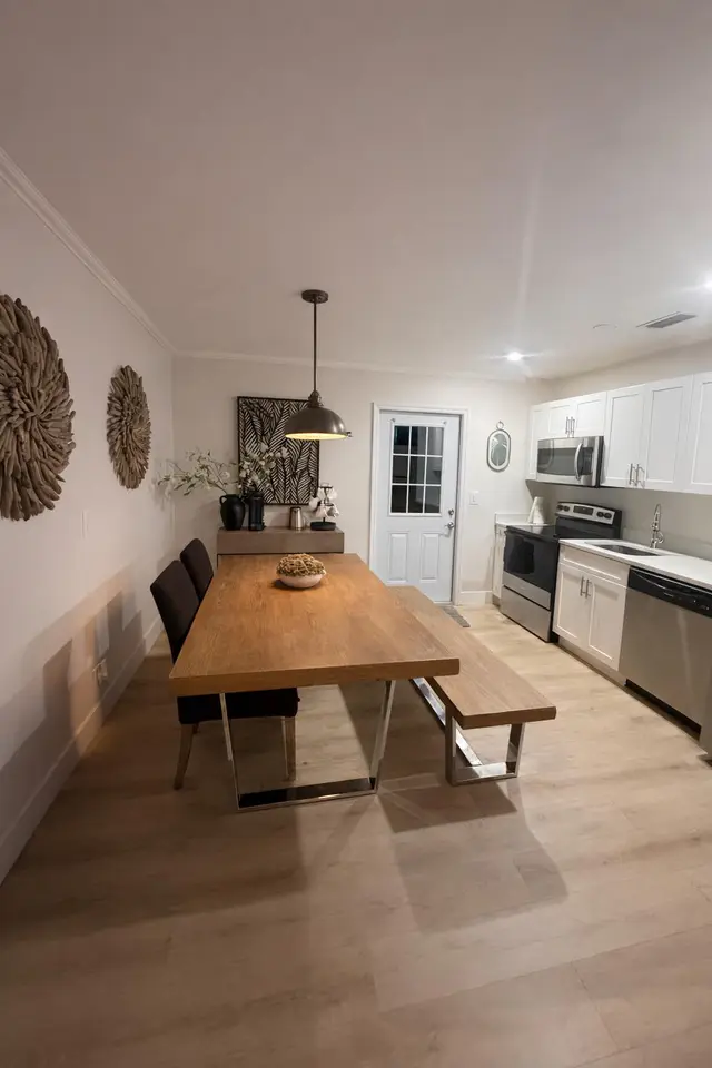 Dining area at Even Keel with a long wooden table and bench, and the white kitchen behind