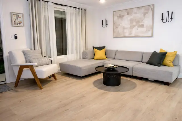 Living room at Even Keel with a light grey sectional sofa, yellow cushions and a wooden floor