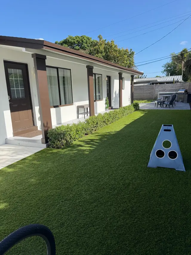 Turf yard at Even Keel with a cornhole board beside the duplex