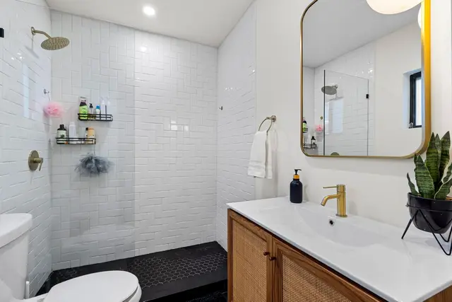 Bathroom at Light House with a walk-in shower, white tiles and a gold-framed mirror