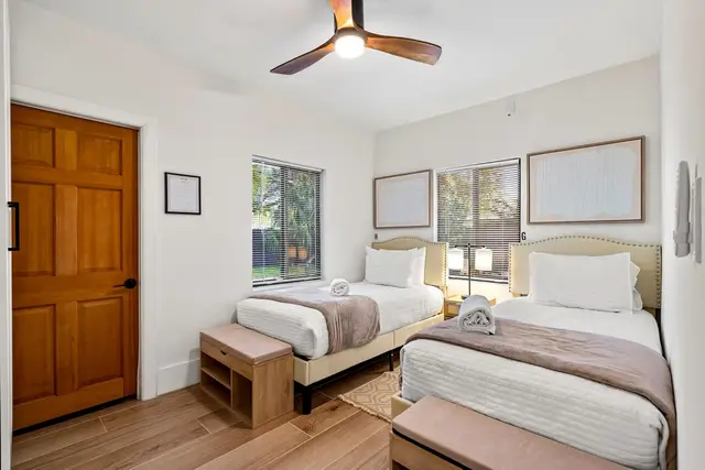 Bedroom at Light House with two twin beds, a wooden door and a ceiling fan
