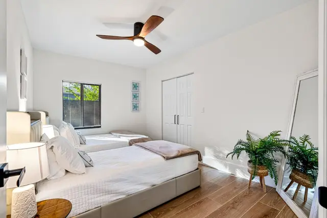 Bedroom at Light House with two beds, a ceiling fan and potted plants
