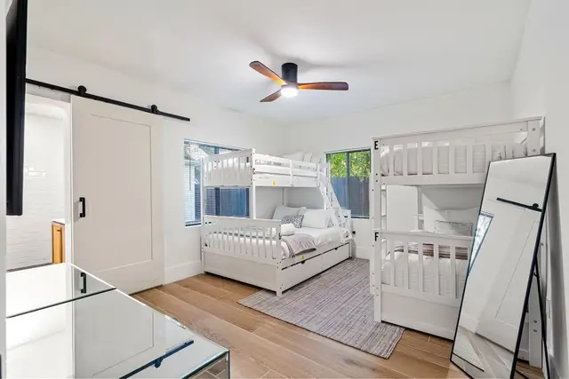 Bedroom at Light House with two sets of white bunk beds and a sliding barn door