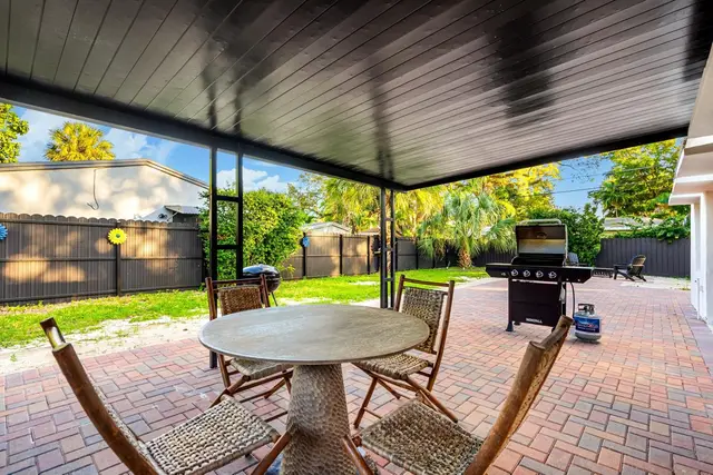 Covered patio at Light House with a round table and chairs, a grill and a fenced backyard