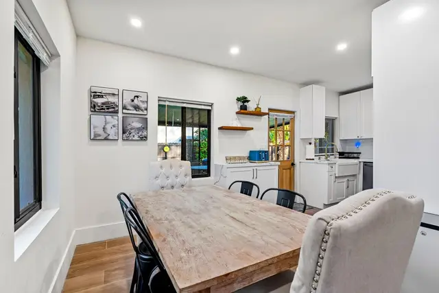 Dining table at Light House with upholstered and black chairs, and the kitchen behind