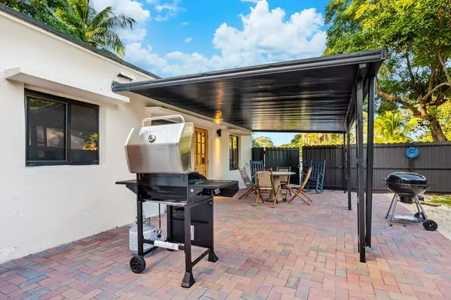 Back of Light House with a covered patio, a gas grill and a brick-paved yard
