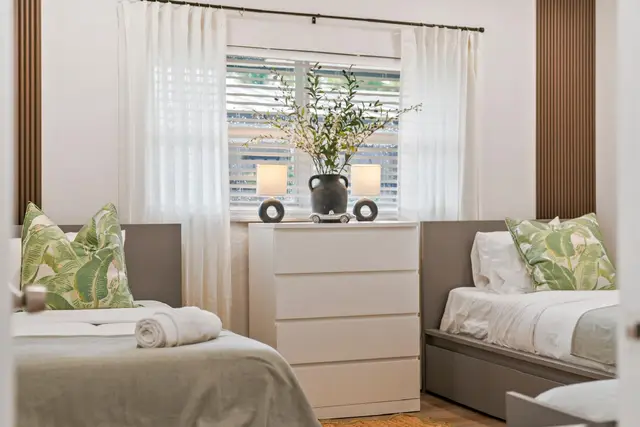 Twin bed at Lily Pad with leaf-print pillows beside a white dresser