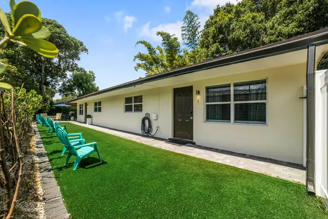 Outside Lily Pad: a white single-storey duplex with a green lawn and teal Adirondack chairs