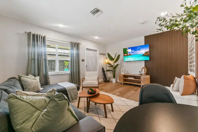 Living room at Lily Pad with a grey sectional sofa, green cushions, round wooden coffee tables and a TV