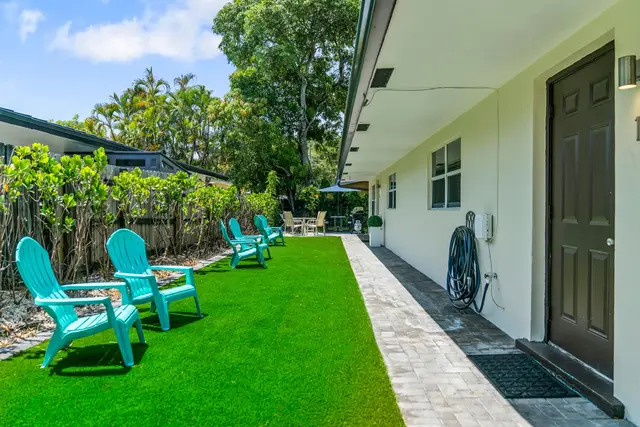 Side lawn at Lily Pad with teal Adirondack chairs along the building