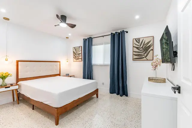 Furnished bedroom at The Gulch with a queen bed, blue curtains and a ceiling fan