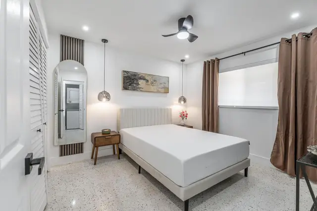 Bedroom at The Gulch with a bed, pendant lights, an arched mirror and brown curtains