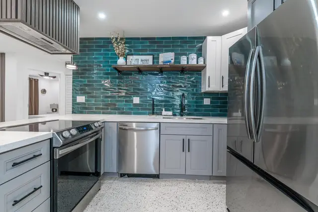 Kitchen at The Gulch with stainless steel refrigerator, oven and dishwasher and a teal tiled backsplash