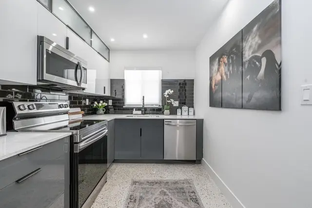 Kitchen at The Gulch with dark grey cabinets, a stainless steel range, microwave and dishwasher