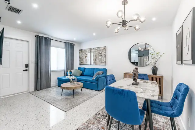 Bright open-plan living and dining room at The Gulch, with a blue sofa, a round coffee table and a dining table with blue chairs