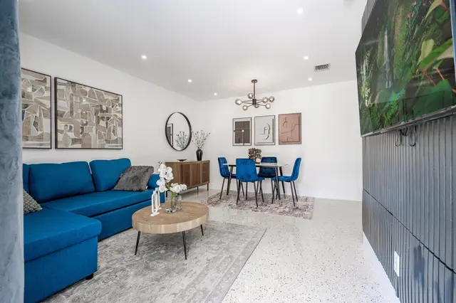 Living room at The Gulch with a blue sectional sofa and a round wooden coffee table, with the dining area beyond