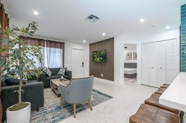 Second living area at The Gulch with grey sofas, a blue armchair, a patterned rug and a tall indoor plant